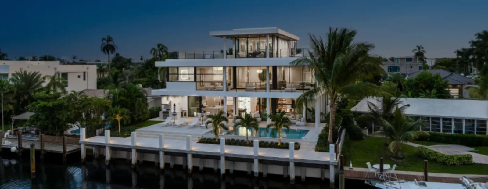 Villa moderne en bord d'eau au crépuscule, terrasses éclairées